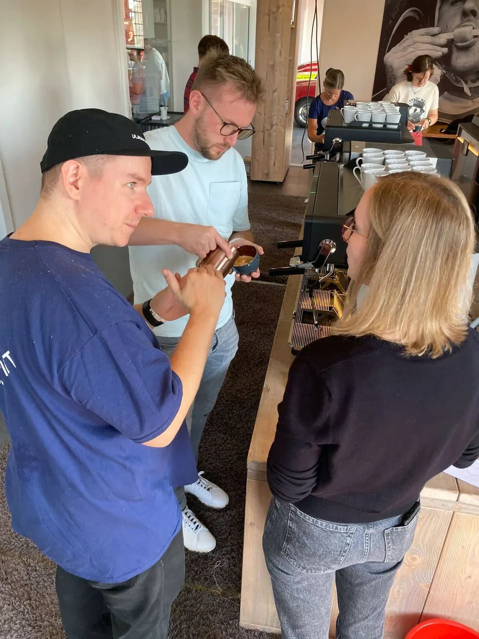 Teilnehmende arbeiten im Trainingsraum gemeinsam an der Espressomaschine