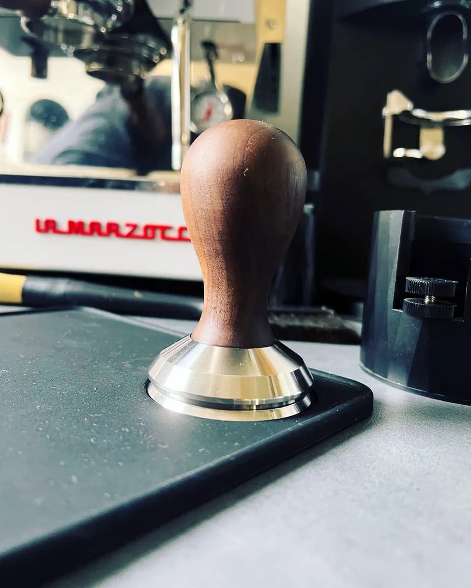 Tamper auf der Arbeitsfläche neben der Siebträgermaschine