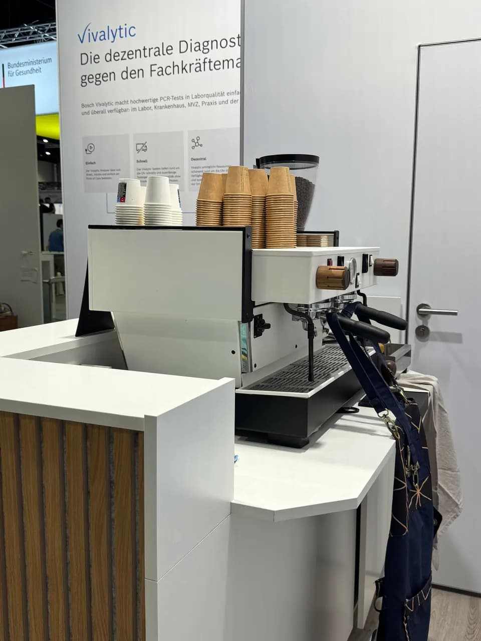 In einen Messestand eingebaute Kaffeebar mit Espressomaschine und Bechertürmen