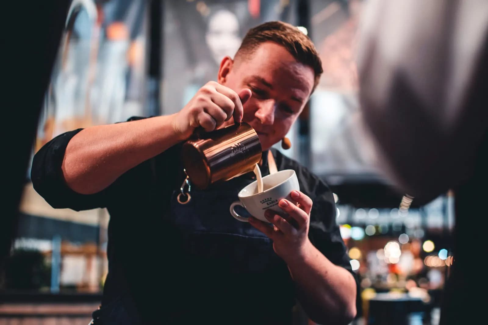 Kai Mößner gießt konzentriert ein Latte-Art-Motiv