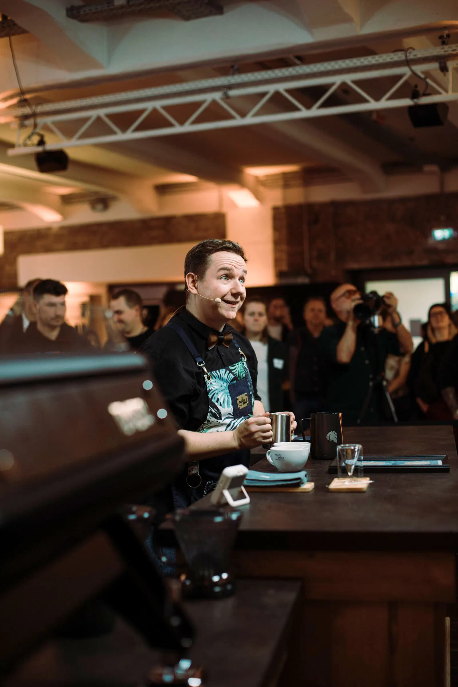 Kai Mößner an der Espressomaschine, dahinter Zuschauer im Saal