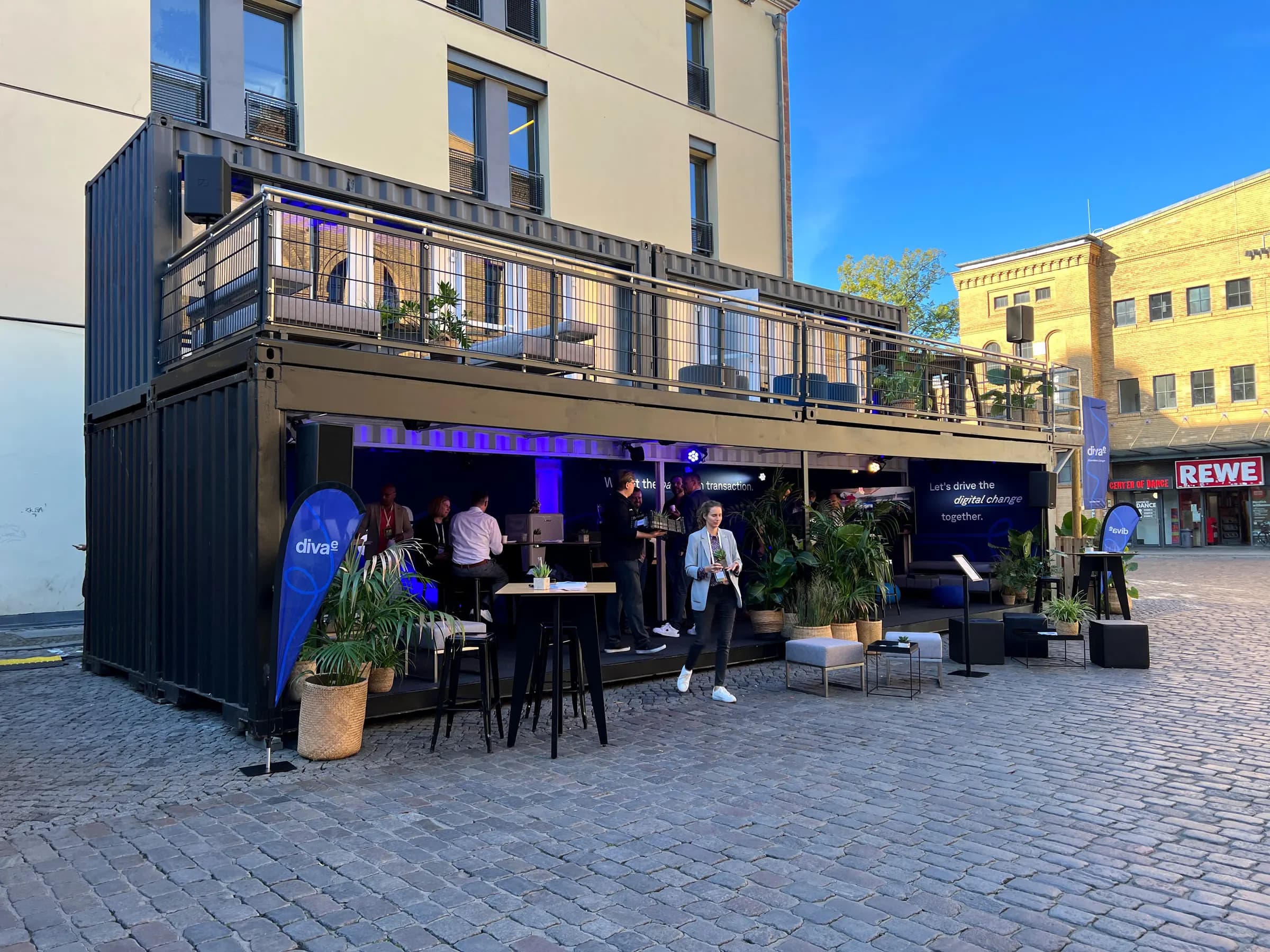 Coffee Bar auf einer Außenfläche am Abend, Gäste an Stehtischen