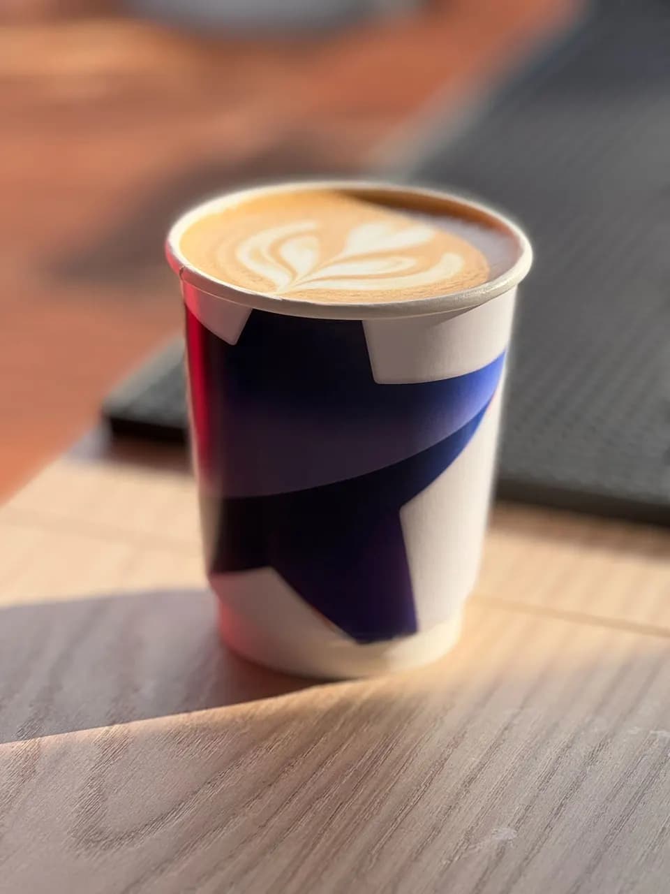 To-go-Becher mit Latte Art auf einem Holztisch