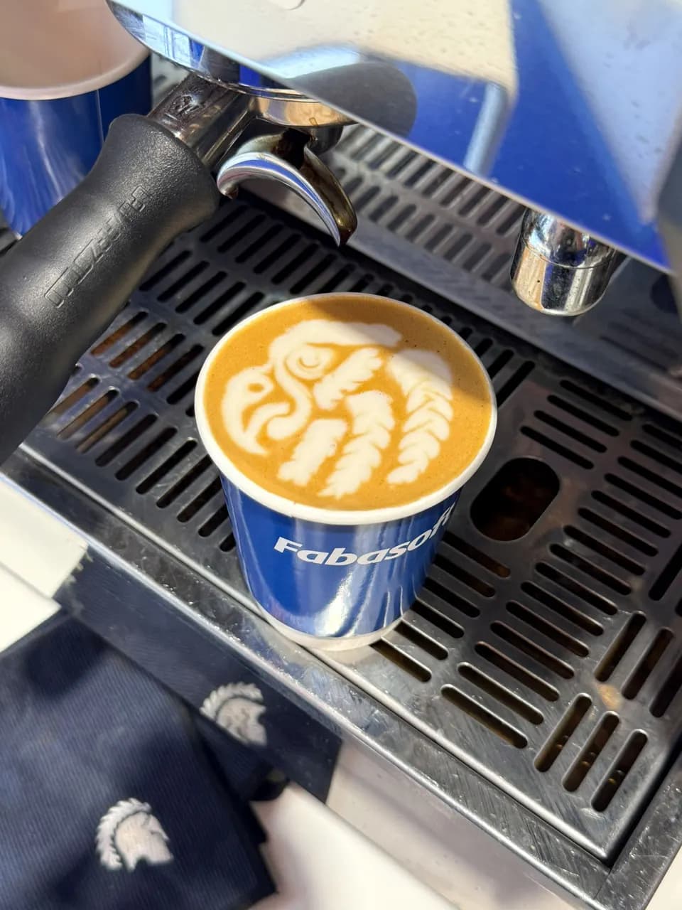 Becher mit Latte Art unter dem Siebträger einer Espressomaschine